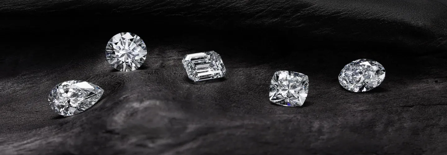 Five natural diamonds in different shapes on dark fabric
